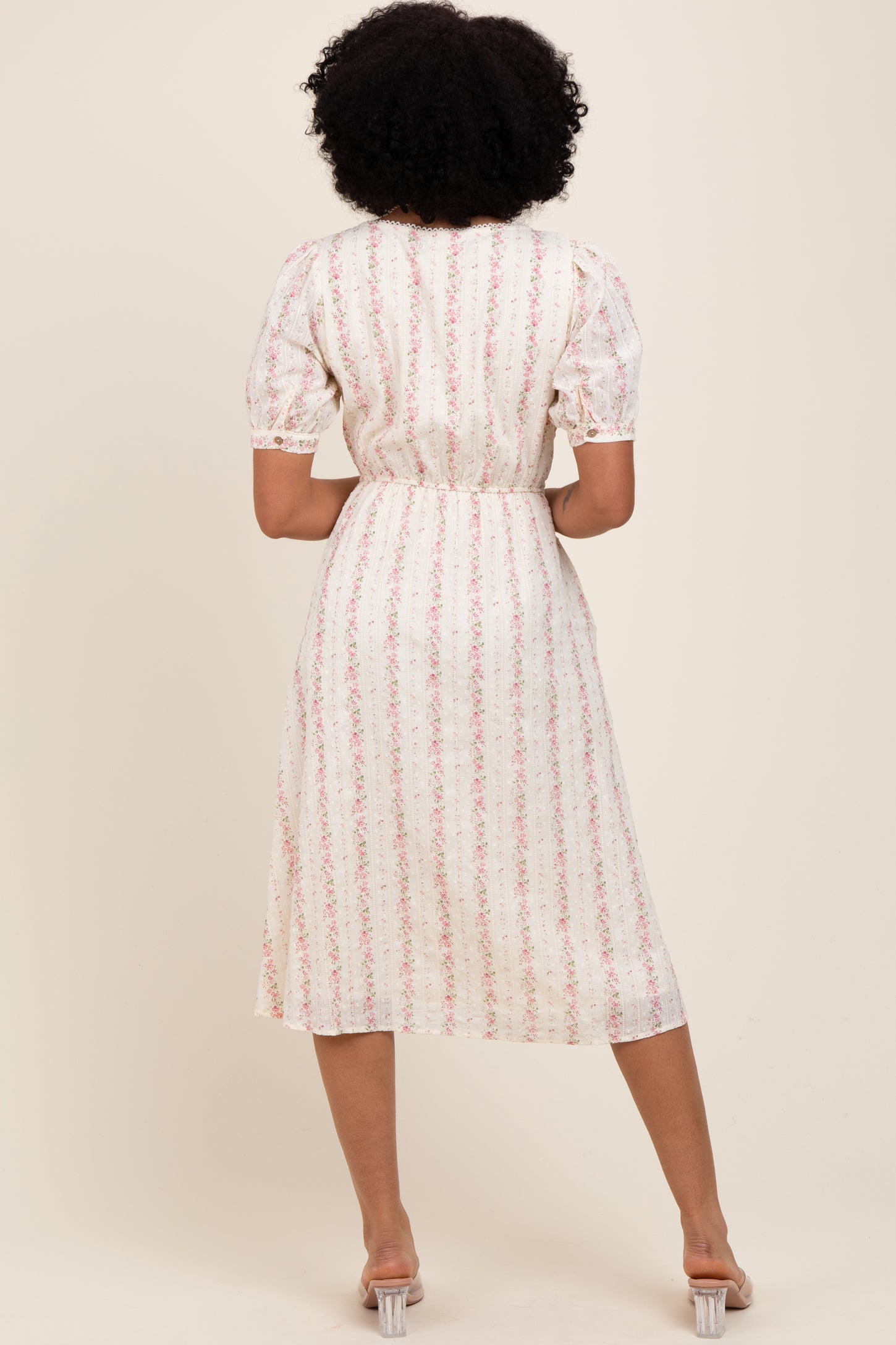 woman wearing a floral print midi dress with puff sleeves and a cinched waist, seen from the back