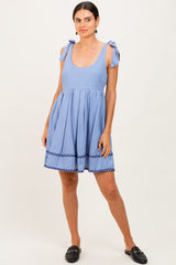 woman wearing a light blue sundress with tie straps and a scalloped hemline