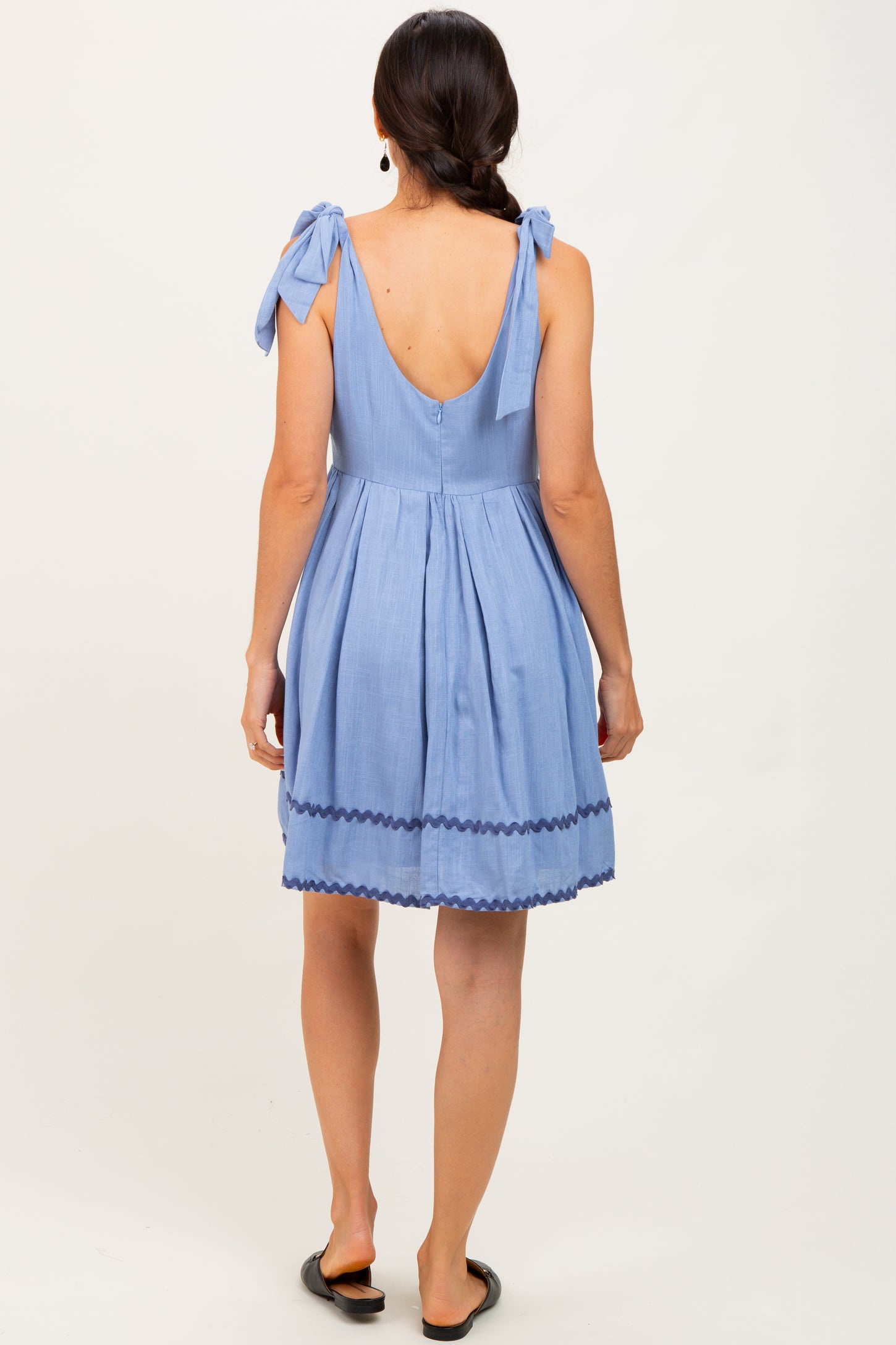 woman wearing a back view of a light blue sundress with tie straps and scalloped hem details