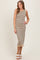 woman wearing a beige and black striped sleeveless midi dress with a ruffled hem and white block heels