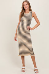 woman wearing a beige and black striped sleeveless midi dress with a ruffled hem and white sandals