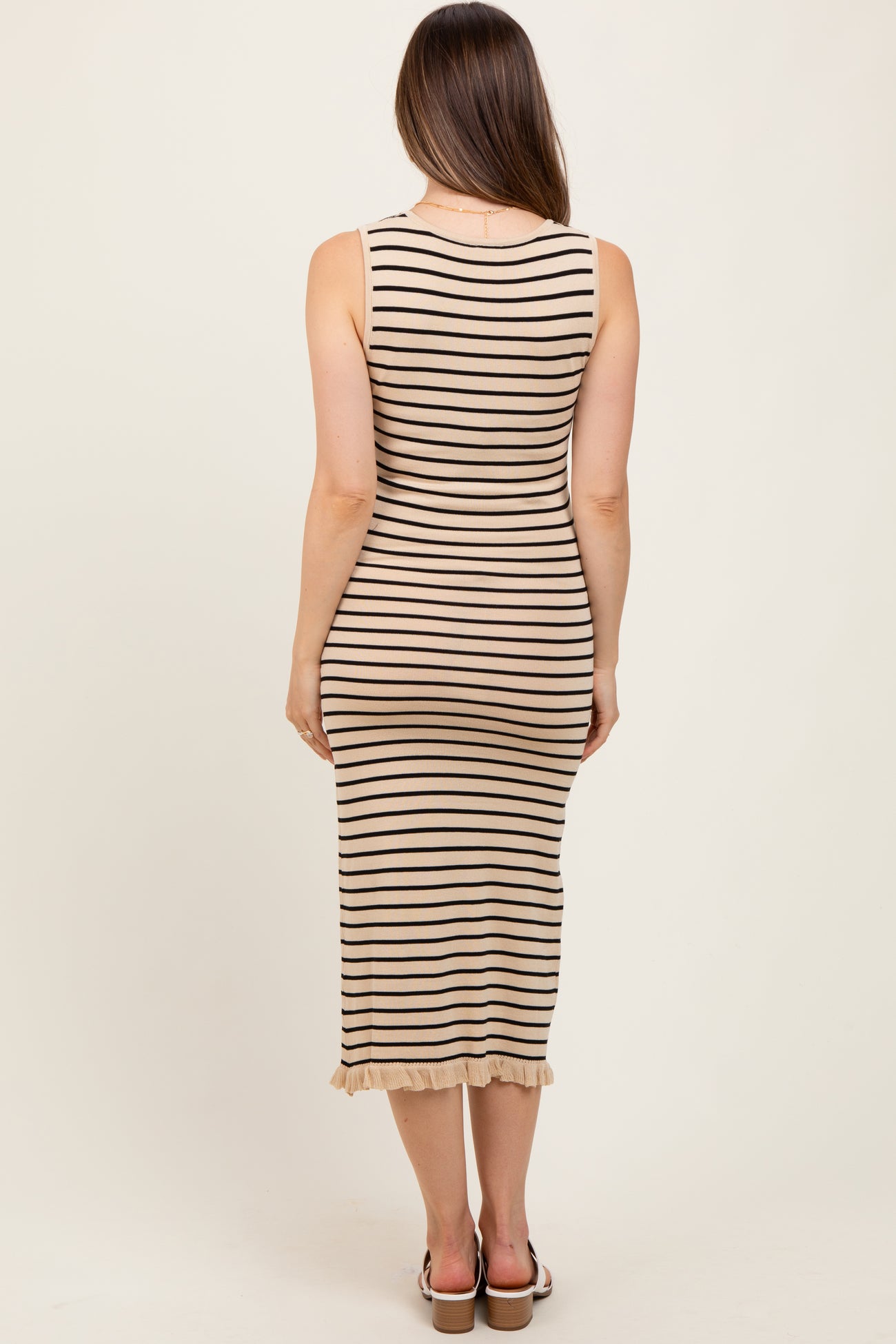 woman wearing a beige and black striped maternity dress with a ruffled hem, viewed from the back