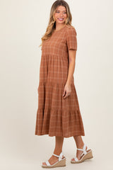 woman wearing a rust-colored short sleeve tiered midi dress with a checkered pattern and white espadrille wedges