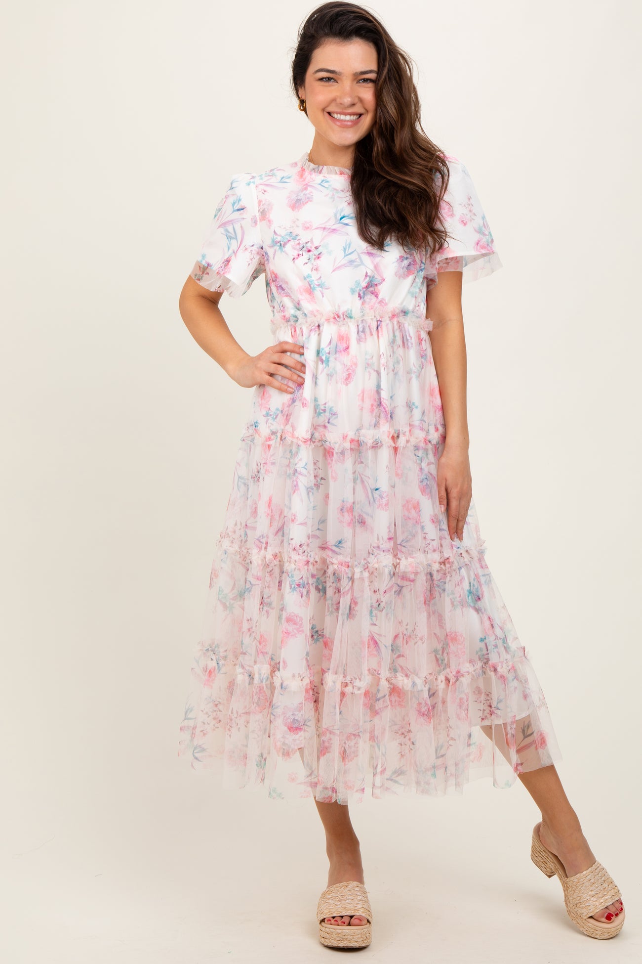 woman wearing a floral tiered maxi dress with short sleeves and a fitted waist standing in a playful pose