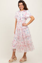 woman wearing a floral tiered midi dress with short sleeves and ruffled details, paired with tan espadrille wedges