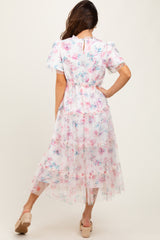 woman wearing a floral print midi dress with short sleeves and a tiered tulle skirt, seen from the back