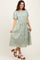 woman wearing a mint green embroidered midi dress with puff sleeves and a tiered skirt, paired with white platform sandals