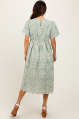 woman wearing a mint green lace midi dress with short sleeves and a cinched waist, showing the back view