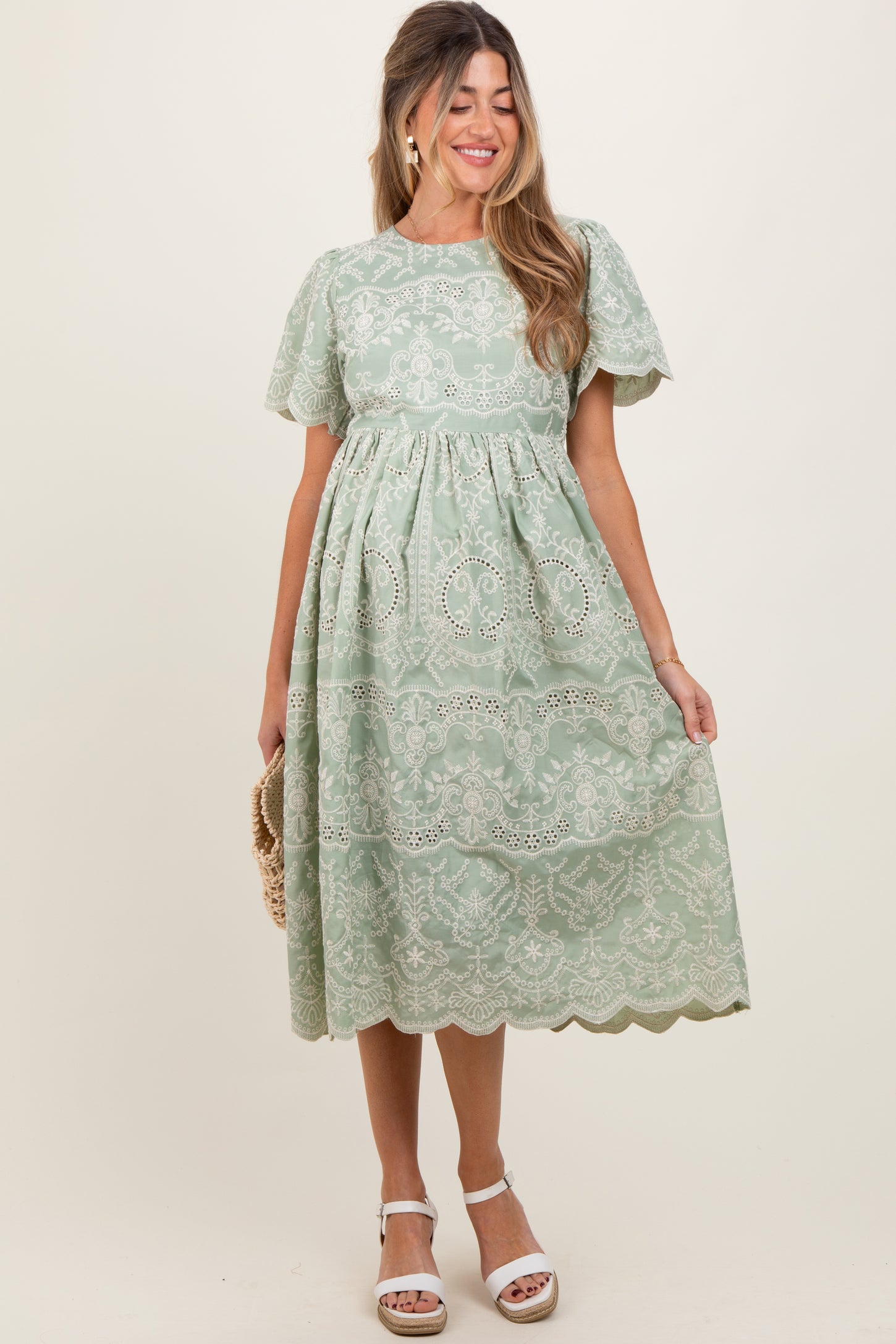 woman wearing a mint green lace trimester dress with short puff sleeves and a flowing skirt, holding a small purse