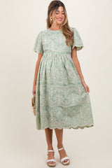 woman wearing a mint green lace trimester dress with short puff sleeves and a flowing skirt, holding a small purse