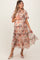 woman wearing a floral tiered maternity dress with short sleeves and holding her baby bump