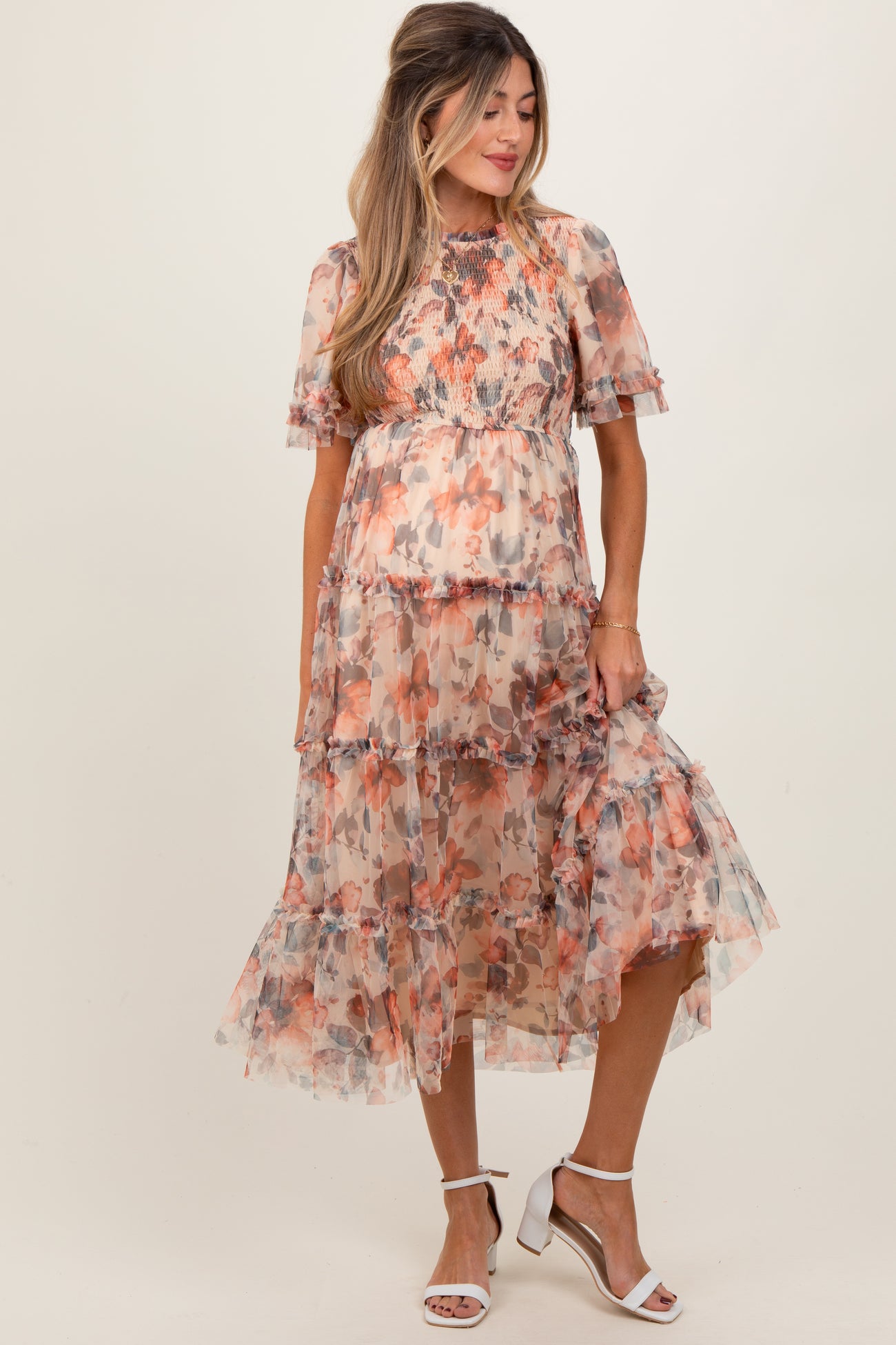 woman wearing a floral patterned maternity dress with short sleeves and ruffle details, showcasing her baby bump