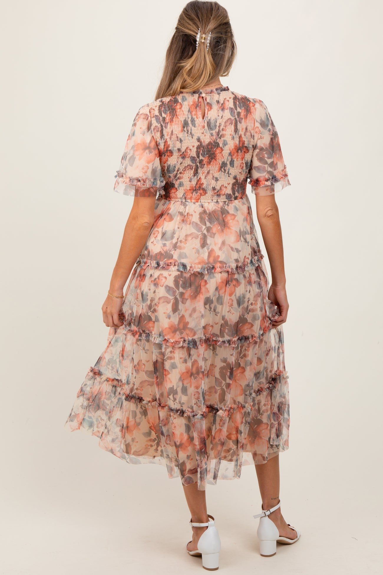 woman wearing a floral maternity maxi dress with tiered ruffles and short sleeves, showing her baby bump from the back