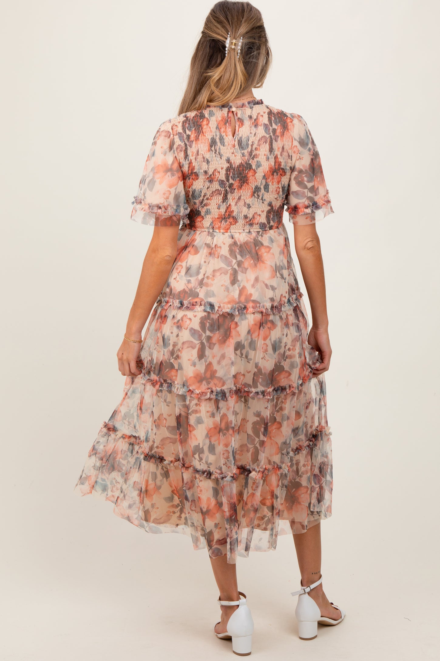 woman wearing a floral maternity maxi dress with tiered ruffles and short sleeves, showing her baby bump from the back
