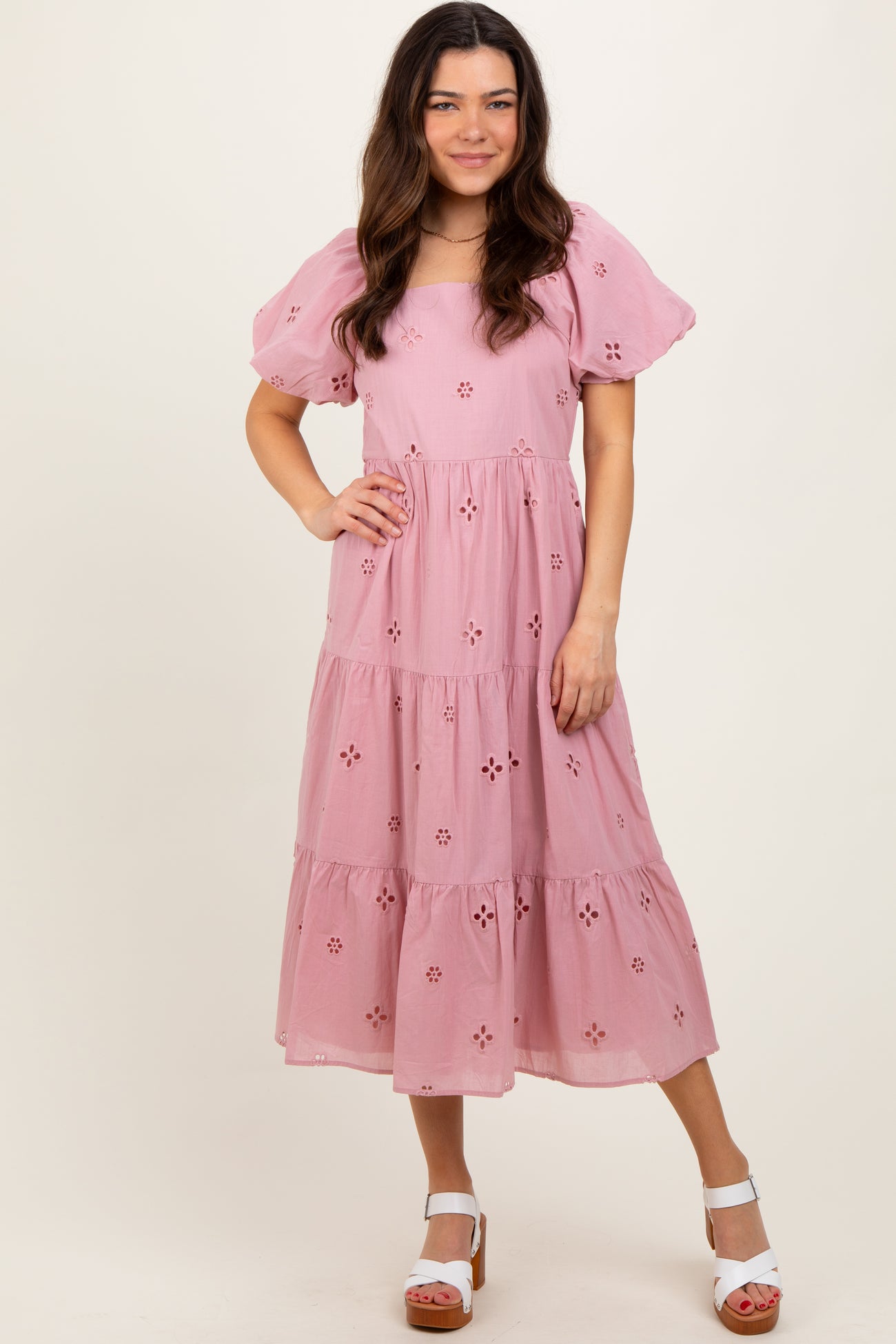 woman wearing a pink floral embroidered midi dress with puff sleeves and tiered skirt