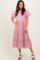 woman wearing a pink floral embroidered midi dress with puff sleeves and tiered skirt