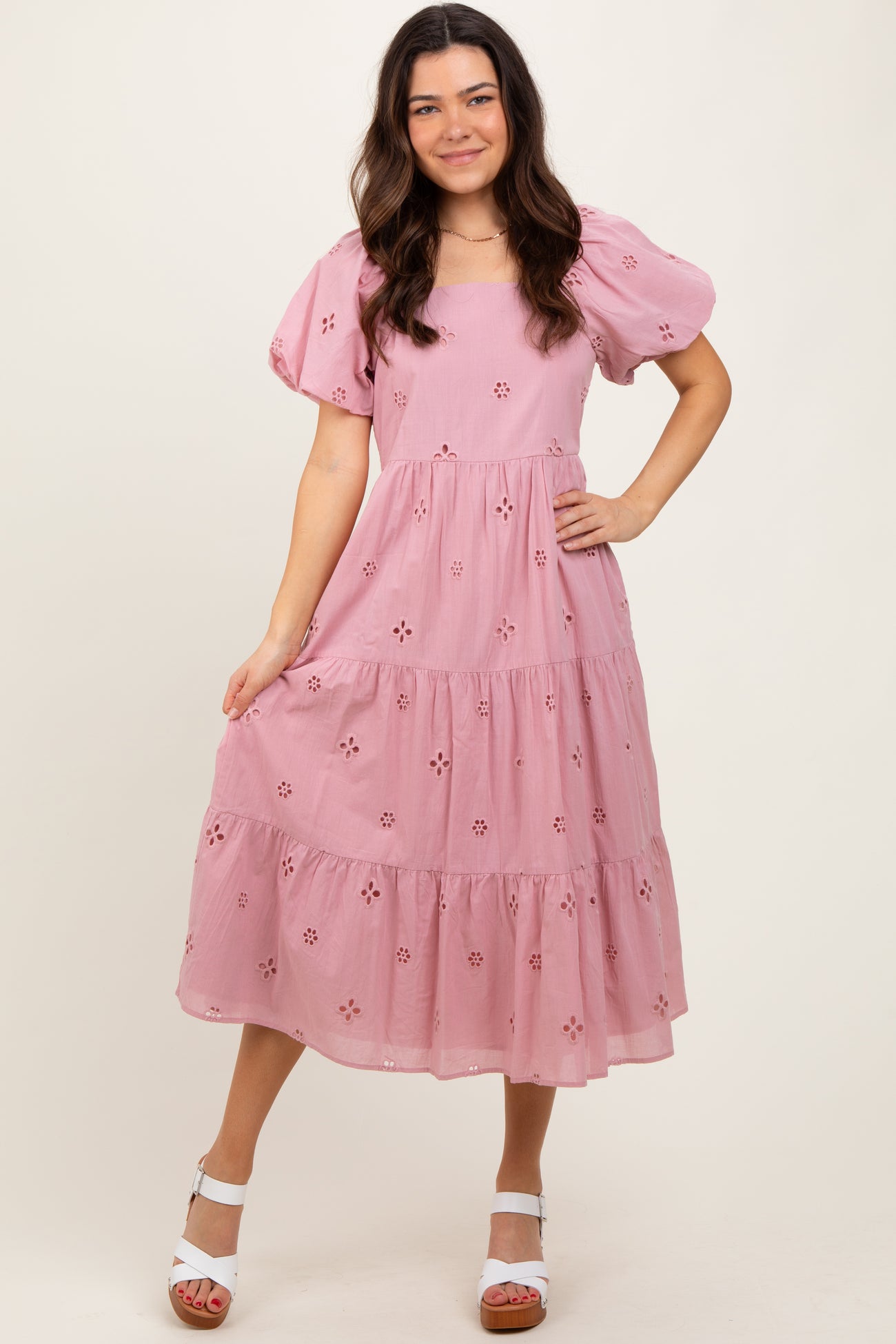 woman wearing a pink puff sleeve midi dress with floral embroidery and a tiered skirt