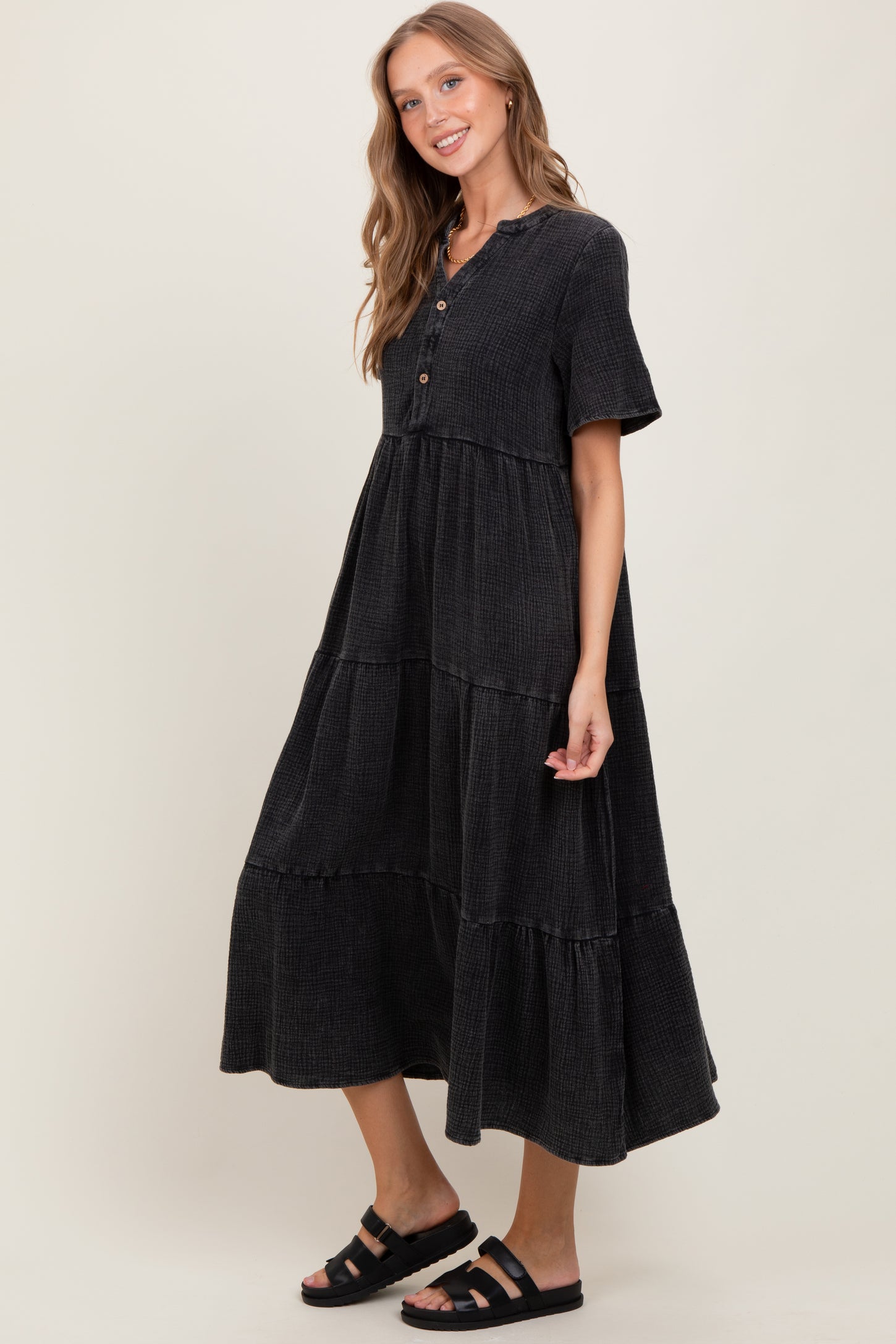 woman wearing a black tiered midi dress with short sleeves and buttons down the front