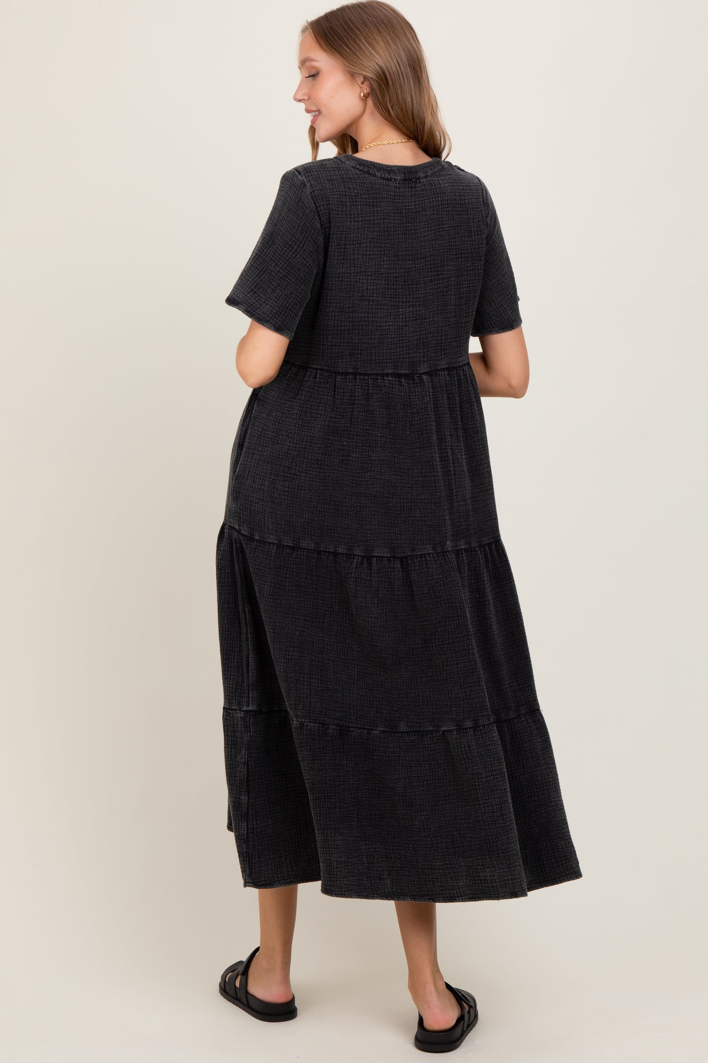 woman wearing a black tiered maxi dress with short sleeves, showing the back view and relaxed fit