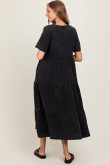 woman wearing a black tiered maxi dress with short sleeves, showing the back view and relaxed fit
