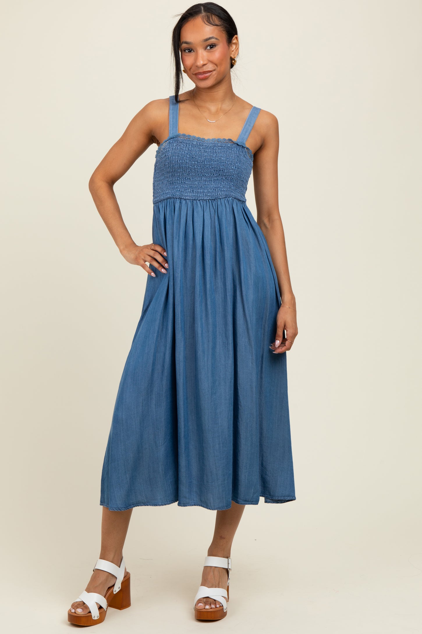 woman wearing a denim blue smocked maxi dress with wide straps and a flowy skirt