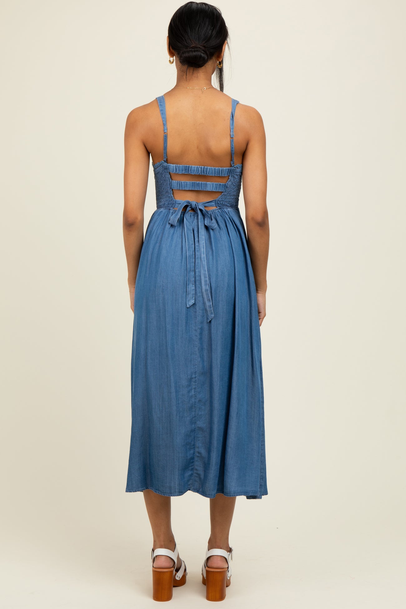 woman wearing a blue chambray midi dress with a smocked bodice and adjustable tie at the back