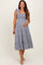 woman wearing a navy and white gingham maternity dress with ruffled straps and a tiered skirt, highlighting her baby bump