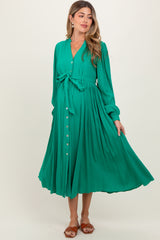 woman wearing a green maternity dress with a tie waist and button-down front, flowing skirt, and long sleeves