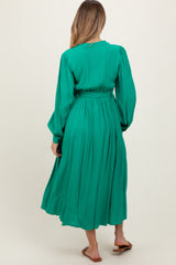 woman wearing a green long sleeve maternity dress with a cinched waist and flowy skirt, seen from the back