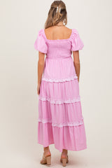 woman wearing a pink striped maternity maxi dress with puff sleeves and tiered ruffle details, viewed from the back