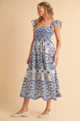 woman wearing a blue and white patterned midi dress with ruffled sleeves and flattering smocked bodice