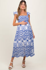 woman wearing a blue and white patterned maternity maxi dress with ruffled sleeves and holding her baby bump
