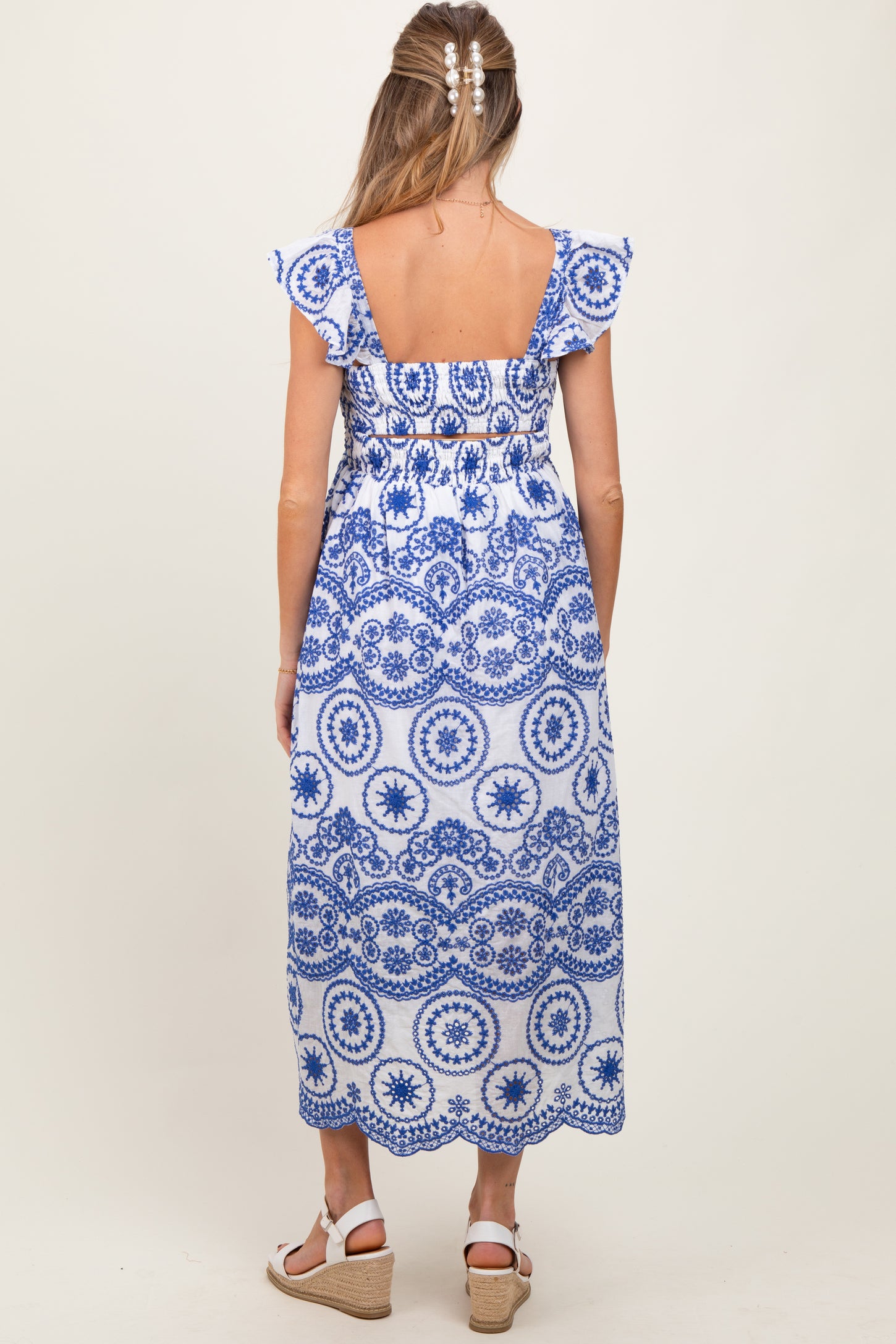 woman wearing a blue and white patterned maternity maxi dress with ruffled sleeves, showing a baby bump