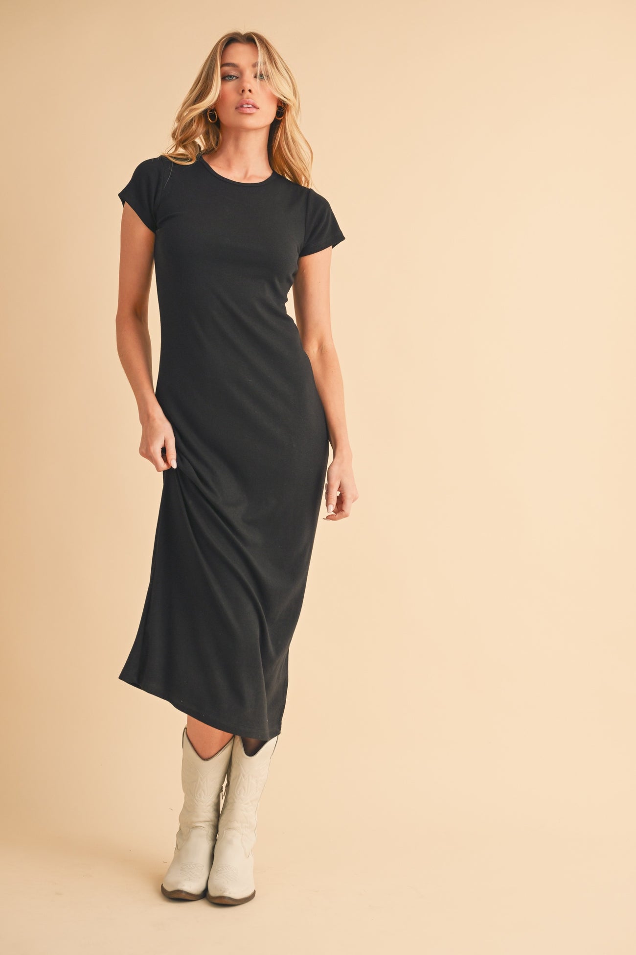 woman wearing a black fitted midi dress and white cowboy boots