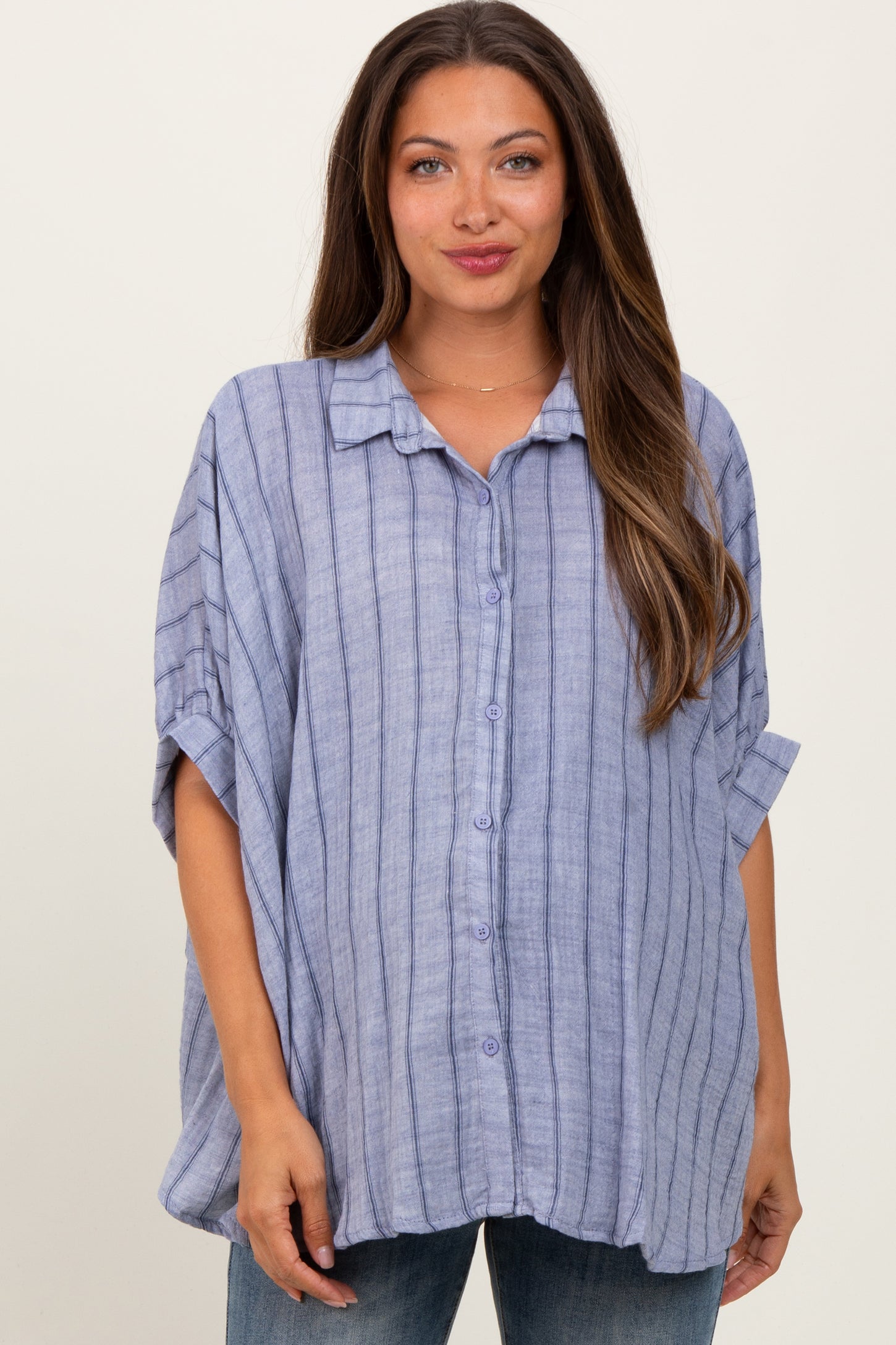woman wearing a light blue striped maternity top with a button-down front and relaxed fit