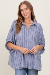 woman wearing a light blue striped oversized button-up shirt with dropped sleeves and a relaxed fit
