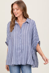 woman wearing a light blue striped button-up shirt with rolled sleeves and a relaxed fit