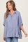 woman wearing a light blue striped button-up shirt with rolled sleeves and a relaxed fit