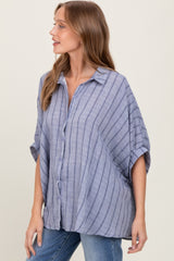 woman wearing a blue striped oversized button-up shirt with short sleeves and relaxed fit paired with jeans