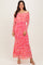 woman wearing a pink floral off-the-shoulder maxi dress with long sleeves and a fitted silhouette