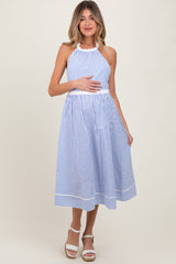 woman wearing a blue and white striped maternity dress with a halter neck, holding her baby bump