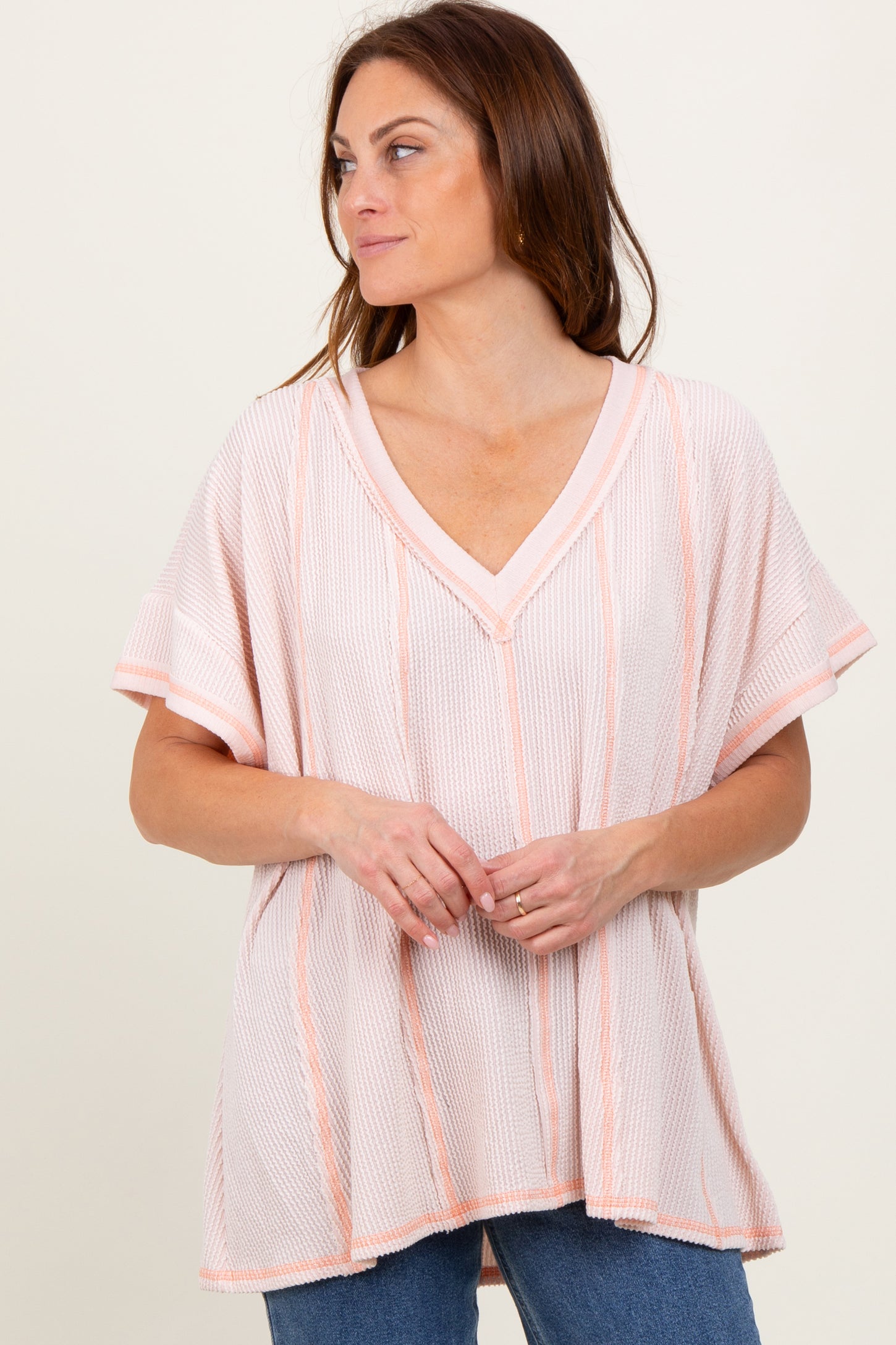 woman wearing a light pink striped short sleeve oversized top with a v-neckline and relaxed fit
