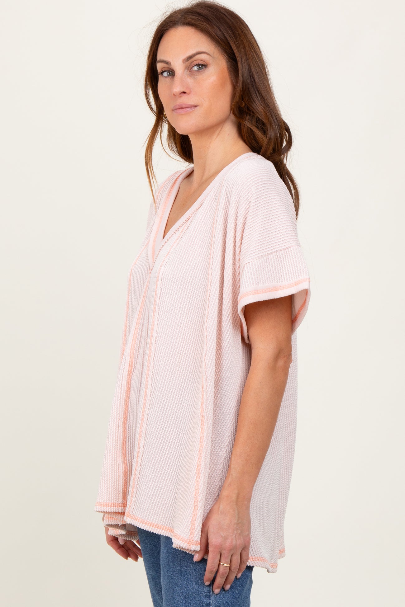 woman wearing a light pink and white striped short sleeve tunic top with a v-neckline and relaxed fit