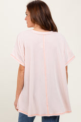 woman wearing a light pink oversized top with short sleeves and a back seam detail, styled with denim jeans