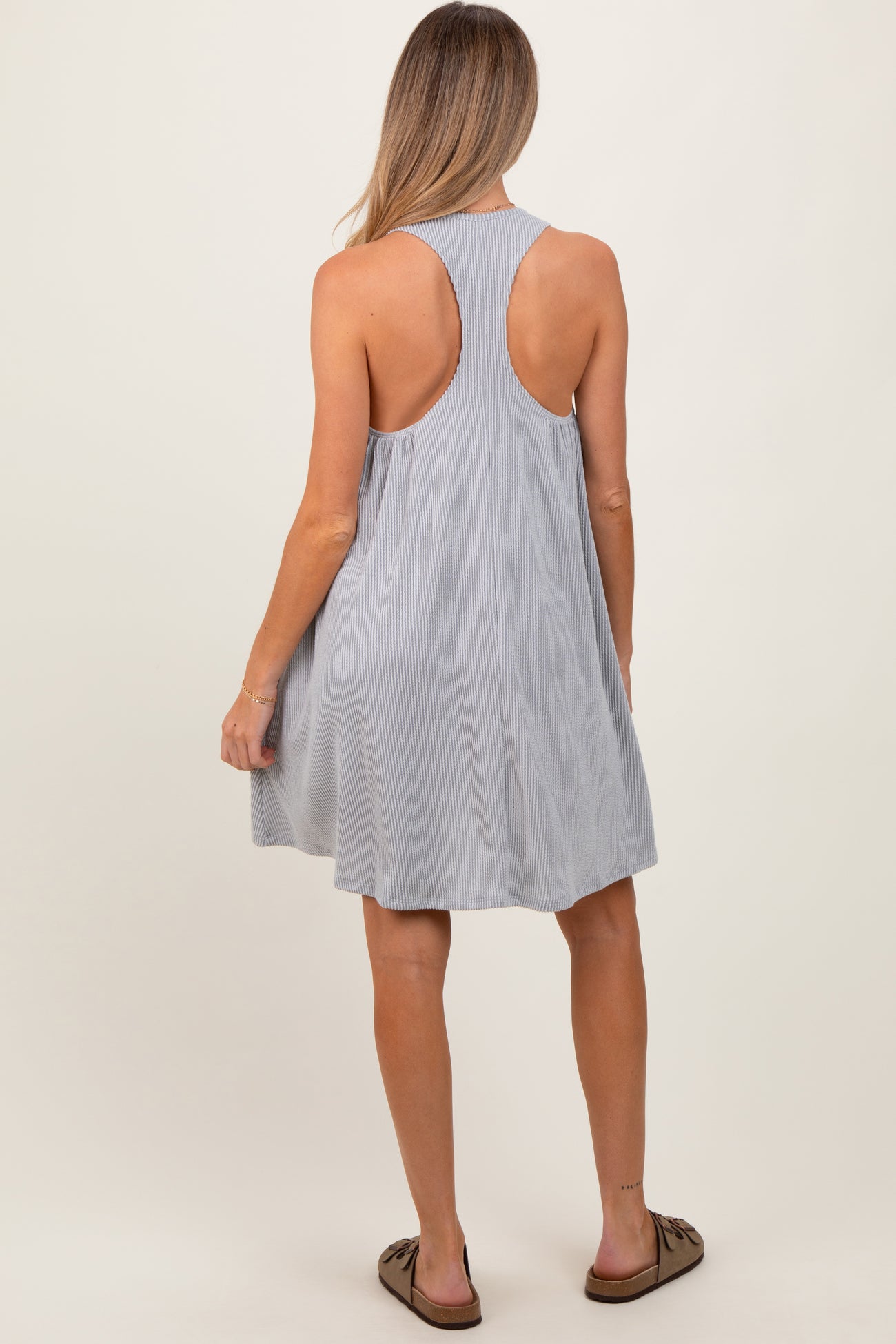 woman wearing a light gray striped sleeveless maternity dress with a relaxed fit, seen from the back