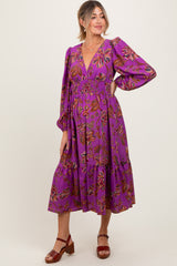 woman wearing a purple floral print maternity dress with a deep V-neck and puff sleeves, showcasing her baby bump