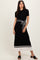 woman wearing a black ribbed midi dress with short sleeves and a white and black striped hem, styled with a belted waist