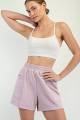 woman wearing a beige cropped tank top and light purple high-waisted shorts with pockets