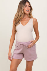 woman wearing a beige maternity tank top and light mauve maternity shorts, showing her baby bump