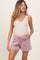 woman wearing a beige maternity tank top and light mauve maternity shorts, showing her baby bump